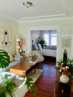 a living room filled with furniture and lots of greenery on top of wooden floors