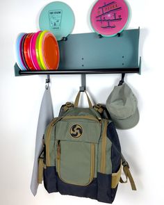 a backpack and frisbees are hanging on a rack with two discs in it