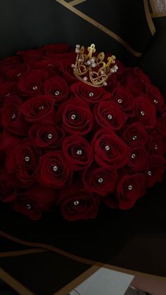 a bouquet of red roses with a gold crown on top is shown in front of a black background