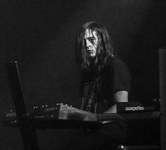 a man with long hair sitting in front of a keyboard and playing an electronic device