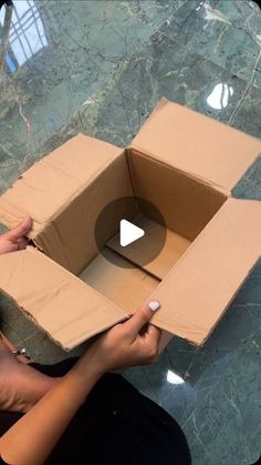 a woman holding a cardboard box with an opening on the inside that has a hole in it