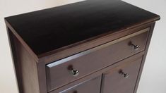 a brown dresser with black top and drawers