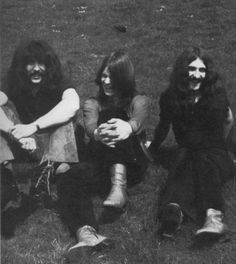 an old black and white photo of four people sitting on the grass