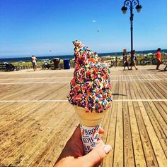 an ice cream cone filled with sprinkles on top of a wooden floor