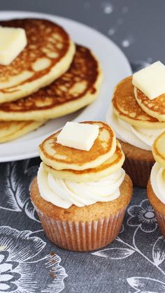 pancakes with butter on top are sitting next to some cupcakes