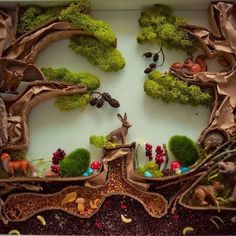 a close up of a tray with trees and animals in the center, surrounded by moss