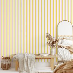 a bedroom with yellow striped wallpaper and a bed in the corner next to a mirror