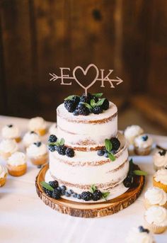 a wedding cake sitting on top of a table with cupcakes in front of it