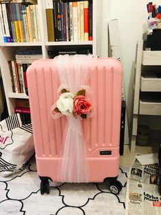 a pink suitcase with a bow and flowers on it in front of bookshelves