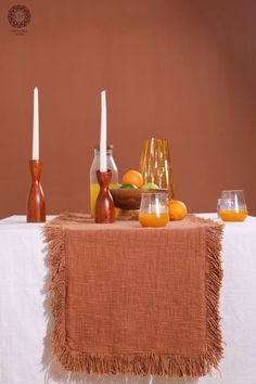 a table topped with candles and fruit on top of a white table cloth covered table