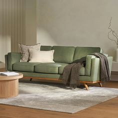 a green couch sitting on top of a wooden floor next to a white rug in a living room