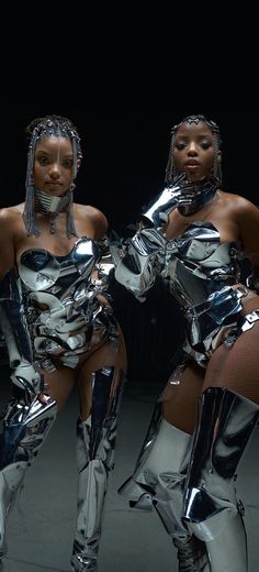 two women dressed in metallic clothing posing for the camera