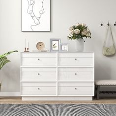 a white dresser sitting in a living room next to a plant