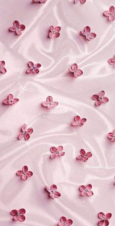 pink flowers are floating in the water on a bed sheet that has been made with satin material