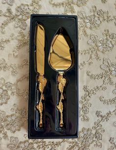 two forks and spoons in a black box on a tablecloth with gold flowers