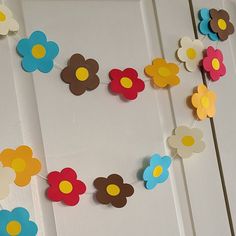 paper flowers are hanging on a white door with yellow, blue, and red ones