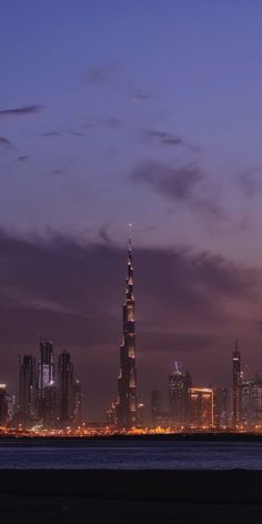 the burj tower is lit up at night, with other tall buildings in the background