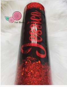 the coca cola bottle has been decorated with red glitter and is sitting on a white fur