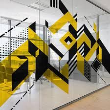 an office cubicle with yellow and black abstract designs on the glass wall, in front of a wooden floor