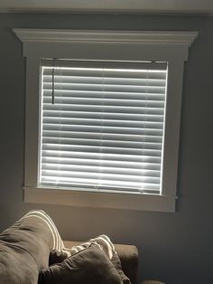 a living room with a brown couch and white blinds