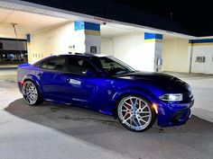 a blue sports car parked in front of a gas station with no one around it