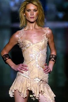 a woman is walking down the runway in a short dress with laces on it