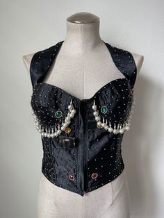 Fabulous primary color jeweled and pearl beaded halter bustier. Cups hare plastic and not wired. Smocked stretch along the sides. Zipper closure in the front. Some missing beads (pictured), but does not take away from the overall look. Halter closure is Velcro. Original tag still attached. Cups look to be a B.  *modeled on size 6 mannequin  Tag reads -  Brand: Maimoon Bali  100% polyester  Size: M  Measurements-  Bust: 34" (before stretch)  Length: 19" Halter straps: 14" each Embellished Fitted Corset For Summer, Black Embellished Corset For Night Out, Fitted Halter Neck Corset For Night Out, Embellished Fitted Summer Corset, Summer Embellished Fitted Corset, Embellished Black Corset For Night Out, Beaded Bustier Top, Luxury Sleeveless Vintage Corset, Black Sleeveless Embellished Corset