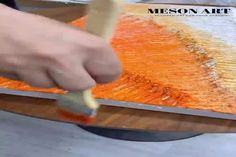 a person is using a brush to paint an orange painting