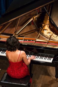 a woman in a red dress sitting at a piano