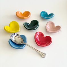 six heart shaped dishes with spoons in the shape of hearts on a white surface