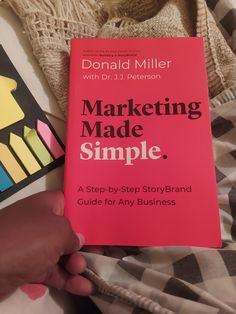 the book marketing made simple is being held by someone's hand on a bed