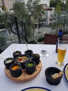 a table topped with food and drinks on top of a white table cloth next to a window