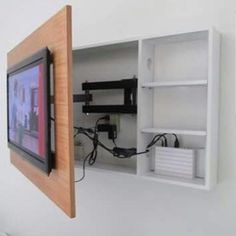 a tv mounted to the side of a wall next to a shelf with wires on it