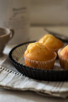 three muffins sitting on top of a metal tray next to a cup of coffee