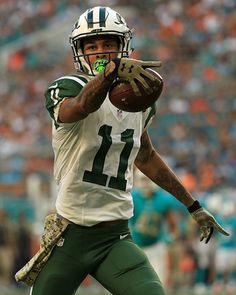 a man holding a football in his right hand and wearing a helmet on the other