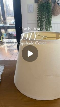 a lamp shade sitting on top of a wooden table next to a potted plant