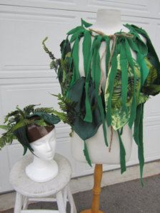 a white mannequin with green leaves on it's head and two potted plants