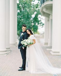 a bride and groom standing in front of columns