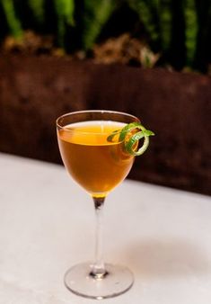 a drink in a glass with a green garnish on the rim sitting on a table