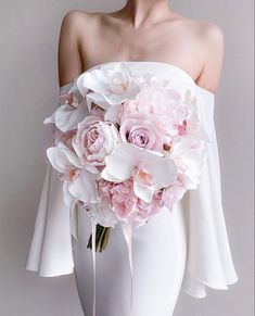 a woman wearing a white dress holding a bouquet of pink and white flowers in her hands