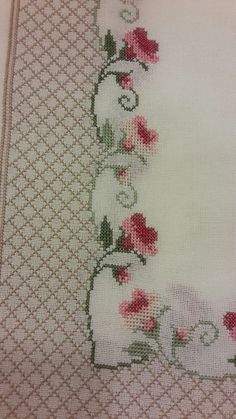 a cross stitch pattern with pink flowers on white fabric and green trim around the edges