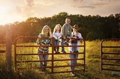 a family standing behind a gate in the grass