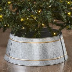 a christmas tree in a metal bucket with lights on it's branches and the base