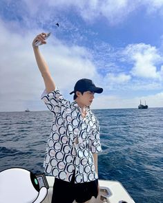 a man standing on top of a boat in the ocean with his arm raised up