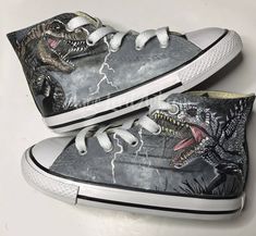 a pair of shoes with dinosaurs painted on them