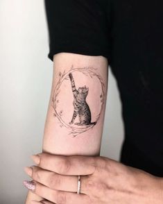 a woman's arm with a cat tattoo on it