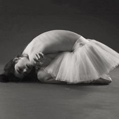 black and white photograph of a woman in a tutu skirt laying on the floor