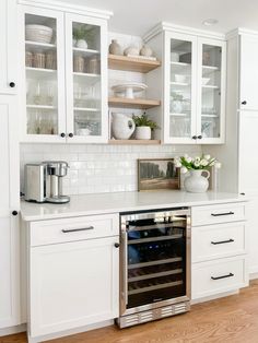 a kitchen with white cabinets and stainless steel oven in the center, built - in wine cooler