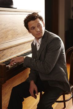 a man sitting at a piano with his hands on the keyboard and looking off to the side