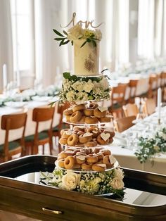 a wedding cake made out of donuts and flowers sits on a tray in the middle of a banquet hall